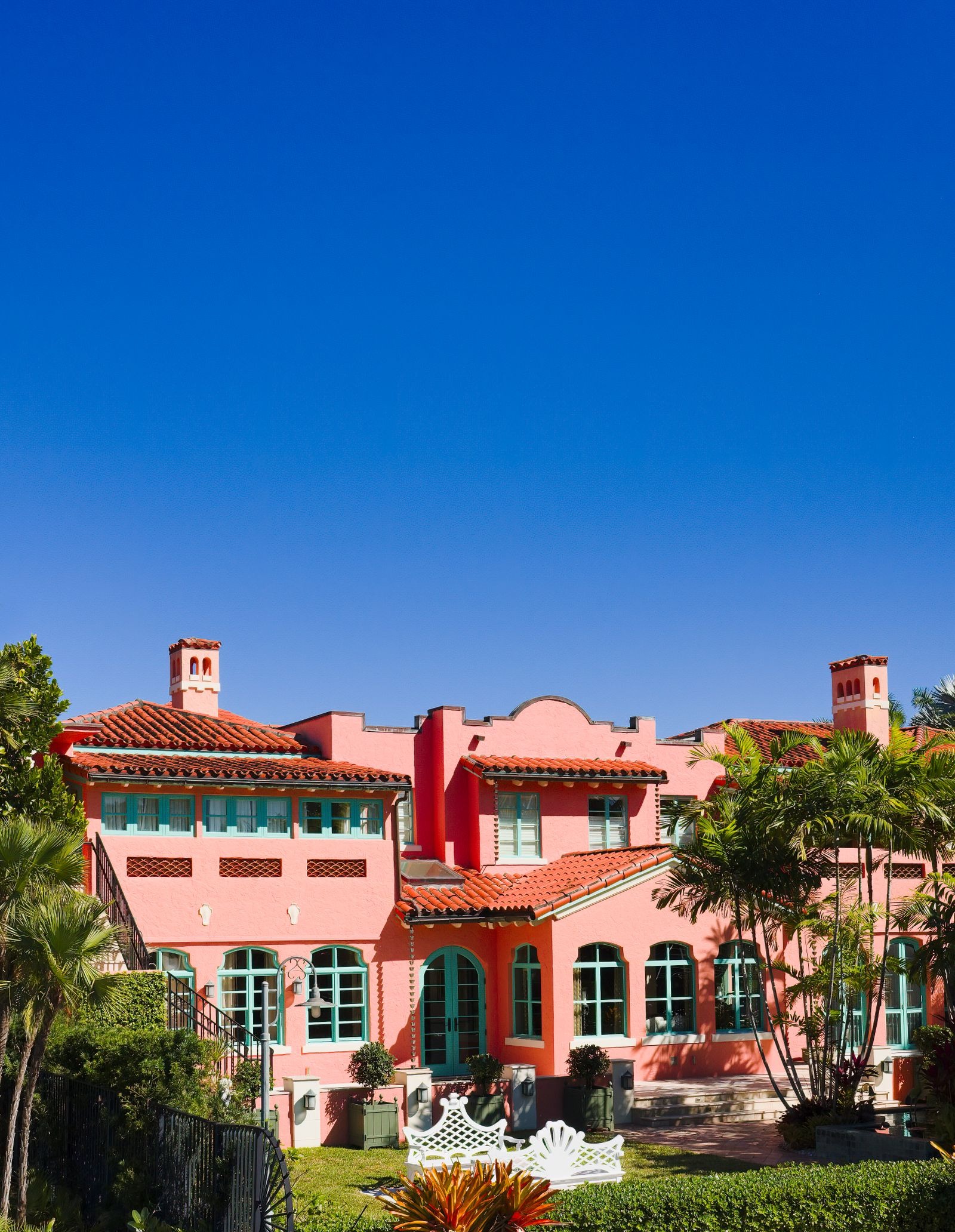 Pink Mediterranean waterfront mansion with palms